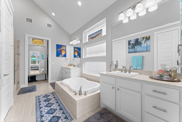 bathroom featuring vanity, tiled tub, and high vaulted ceiling