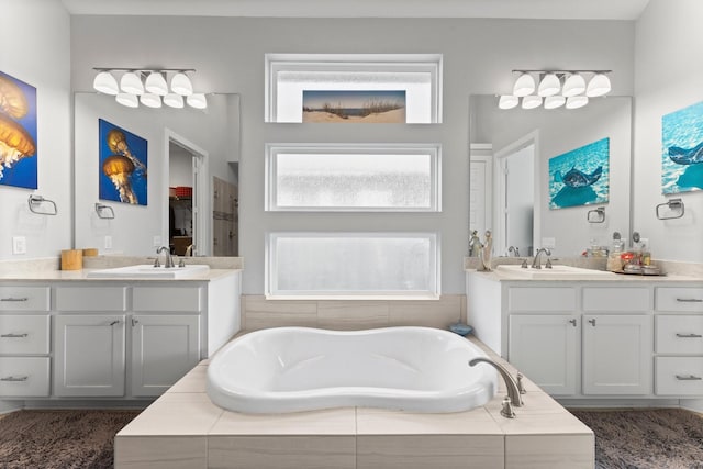 bathroom with vanity and tiled bath