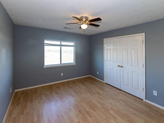 unfurnished bedroom with a closet, a textured ceiling, ceiling fan, and light hardwood / wood-style flooring