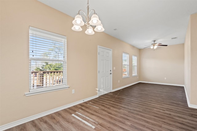 empty room with dark hardwood / wood-style flooring and ceiling fan with notable chandelier