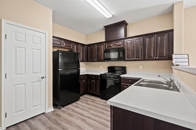 kitchen with sink, dark brown cabinets, black appliances, and light hardwood / wood-style floors