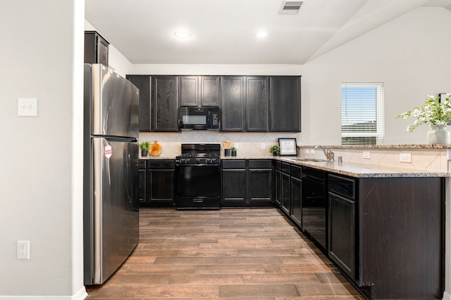 kitchen with black appliances, sink, backsplash, light hardwood / wood-style floors, and light stone counters