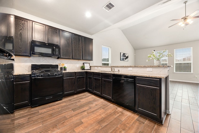 kitchen featuring lofted ceiling, sink, black appliances, hardwood / wood-style flooring, and backsplash