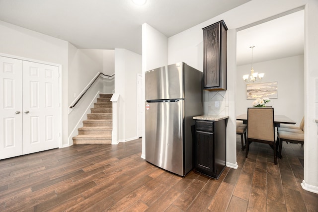 kitchen featuring decorative light fixtures, dark brown cabinets, stainless steel refrigerator, and dark wood-type flooring