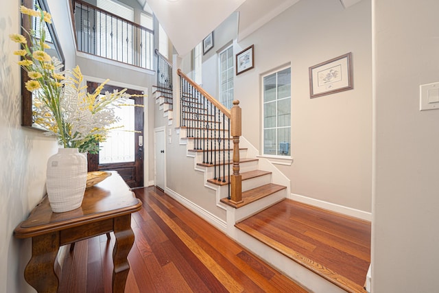 foyer entrance featuring dark wood-type flooring and a towering ceiling