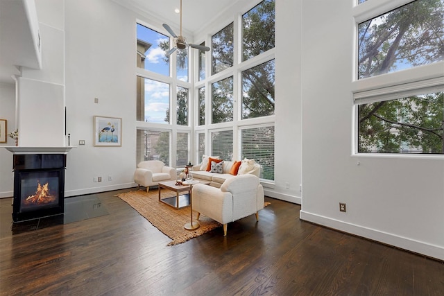 living room with dark hardwood / wood-style floors, ceiling fan, and a high ceiling