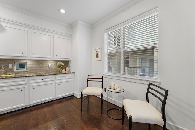 interior space featuring dark wood-type flooring, white cabinetry, dark stone countertops, ornamental molding, and decorative backsplash