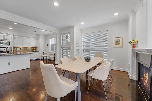 dining space with sink, crown molding, and dark hardwood / wood-style floors