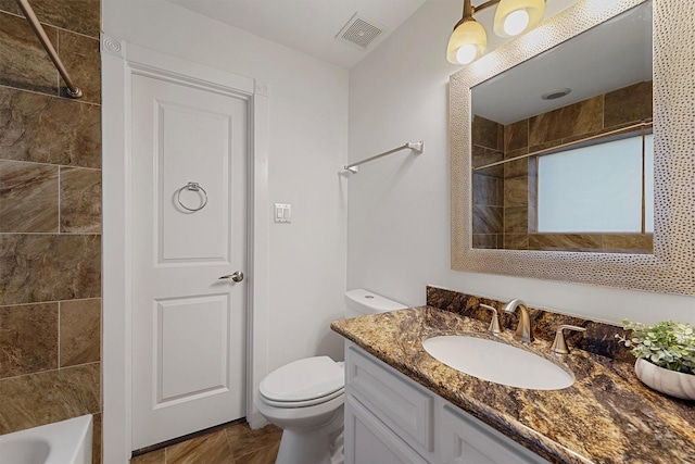 full bathroom featuring tiled shower / bath, vanity, and toilet