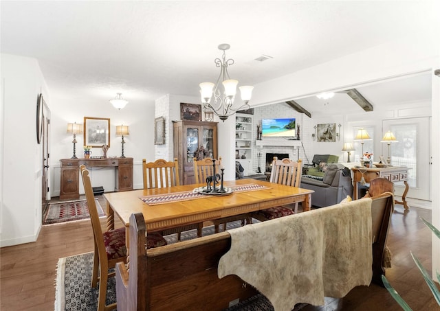 dining room with an inviting chandelier, a brick fireplace, vaulted ceiling with beams, and dark hardwood / wood-style floors