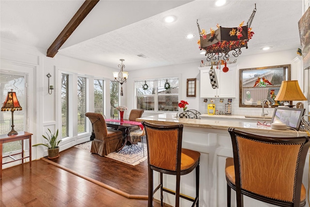 bar featuring an inviting chandelier, tasteful backsplash, white cabinets, dark hardwood / wood-style flooring, and beamed ceiling