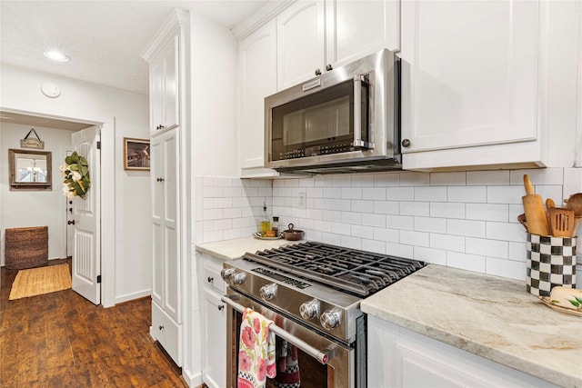 kitchen featuring white cabinetry, light stone counters, dark hardwood / wood-style flooring, stainless steel appliances, and backsplash