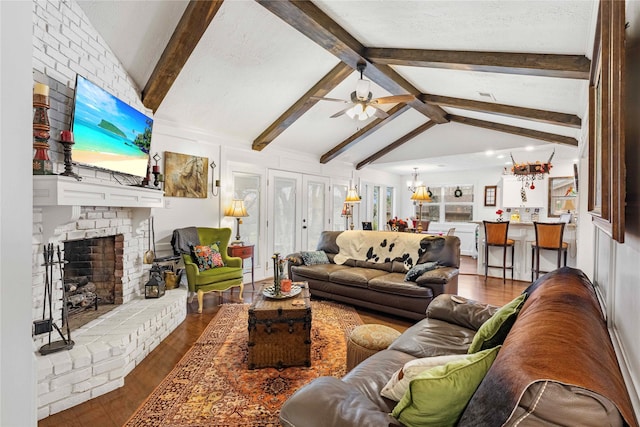 living room with lofted ceiling with beams, hardwood / wood-style flooring, ceiling fan with notable chandelier, and a fireplace