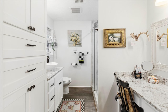 bathroom with hardwood / wood-style flooring, vanity, toilet, and walk in shower