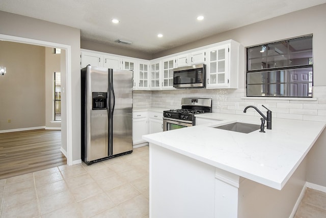 kitchen featuring sink, kitchen peninsula, white cabinets, and appliances with stainless steel finishes