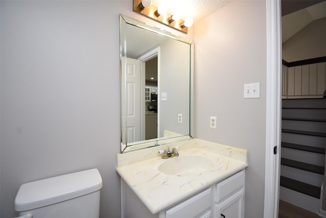 bathroom featuring vanity, a textured ceiling, and toilet