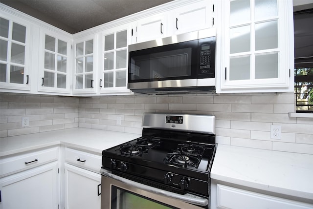 kitchen featuring backsplash, light stone countertops, white cabinets, and appliances with stainless steel finishes