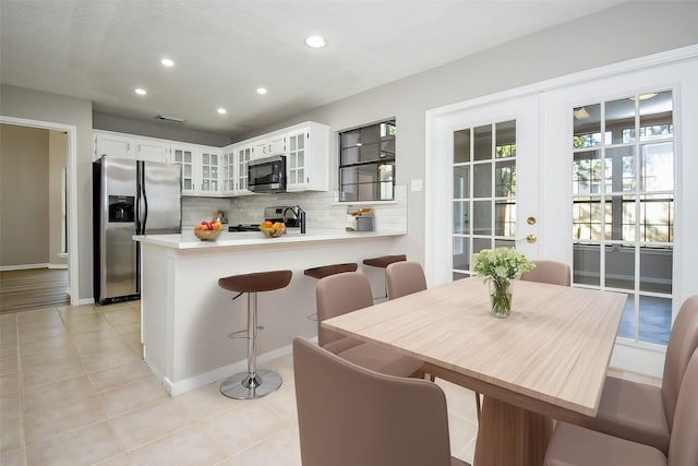 kitchen with white cabinetry, backsplash, stainless steel appliances, french doors, and kitchen peninsula