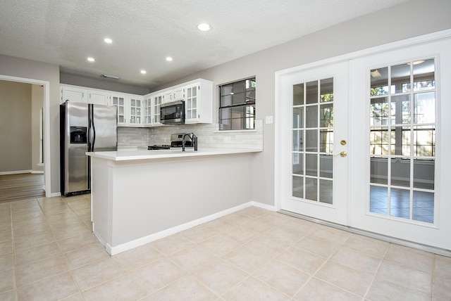 kitchen featuring white cabinetry, a textured ceiling, appliances with stainless steel finishes, kitchen peninsula, and backsplash