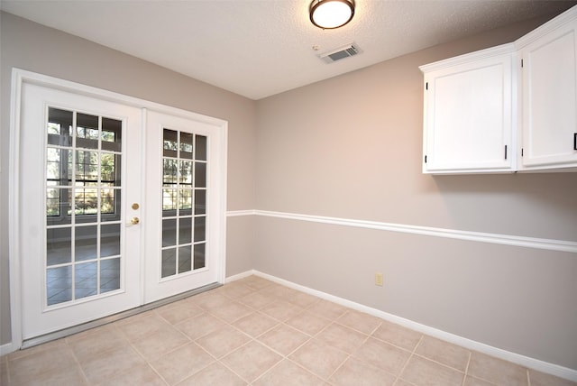 interior space featuring french doors, a textured ceiling, and light tile patterned floors