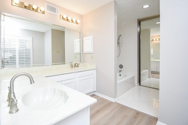 bathroom featuring vanity, tiled shower / bath combo, and hardwood / wood-style floors