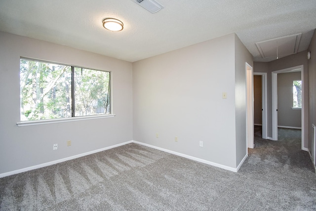 carpeted empty room featuring a textured ceiling