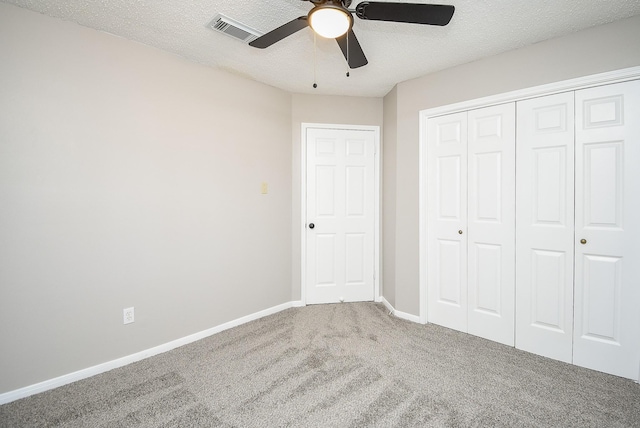 unfurnished bedroom with ceiling fan, a closet, a textured ceiling, and carpet