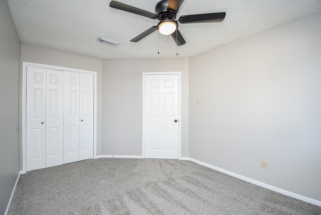 unfurnished bedroom with ceiling fan, carpet floors, a closet, and a textured ceiling