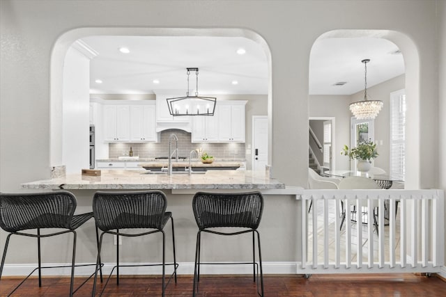 kitchen with white cabinetry, light stone countertops, pendant lighting, and an inviting chandelier