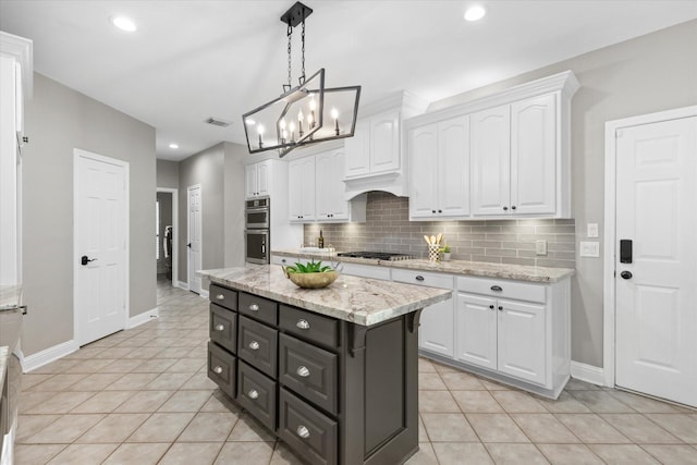 kitchen featuring hanging light fixtures, backsplash, stainless steel appliances, light stone countertops, and white cabinets