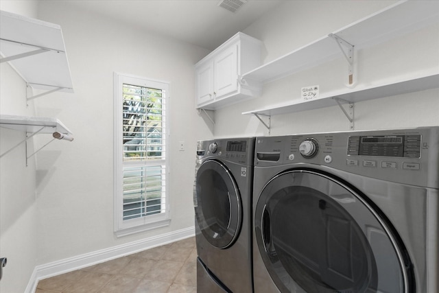 laundry area featuring cabinets, light tile patterned floors, and washing machine and clothes dryer