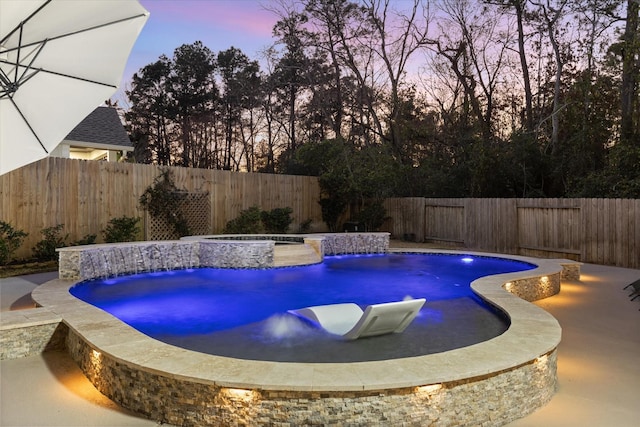 pool at dusk with an in ground hot tub and pool water feature