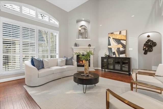 living room featuring hardwood / wood-style flooring, a tiled fireplace, and a high ceiling