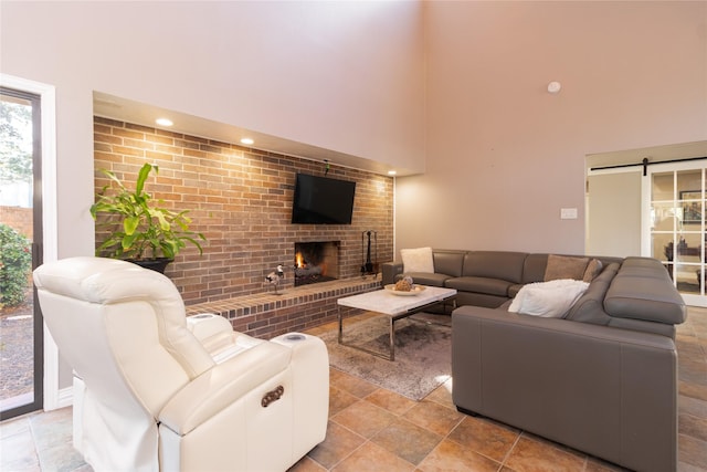 living room featuring a fireplace, a barn door, and a high ceiling