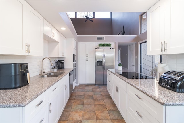 kitchen with sink, light stone countertops, white cabinets, and appliances with stainless steel finishes