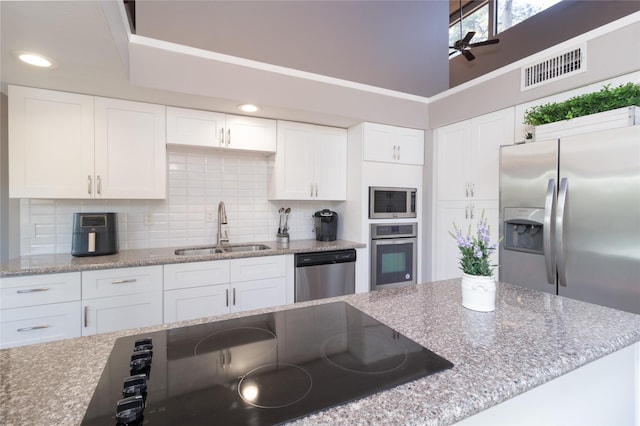 kitchen with sink, white cabinetry, appliances with stainless steel finishes, ceiling fan, and backsplash