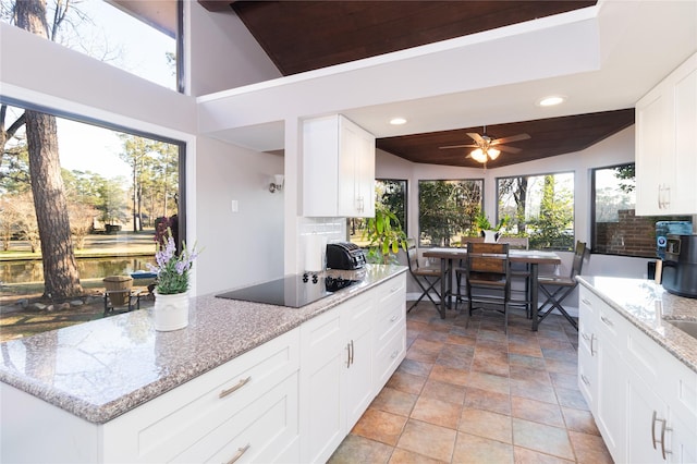 kitchen featuring tasteful backsplash, light stone countertops, black electric stovetop, and white cabinets