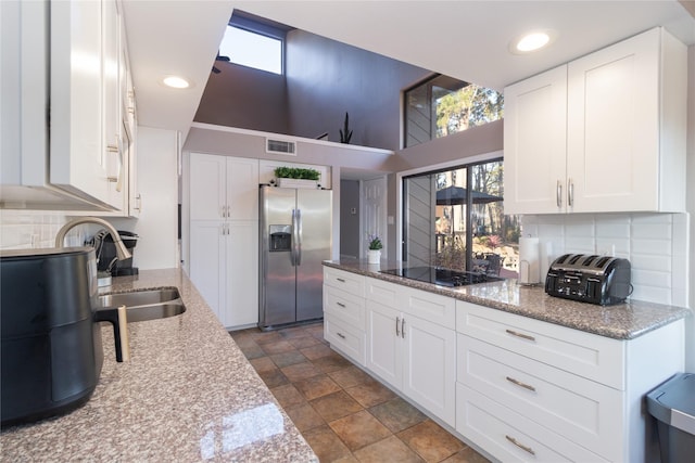 kitchen featuring white cabinetry, sink, stainless steel fridge, decorative backsplash, and black electric stovetop