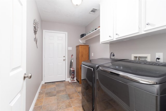 laundry room with washing machine and dryer, cabinets, and a textured ceiling