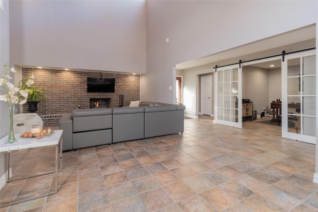 living room with a fireplace, a barn door, and a high ceiling