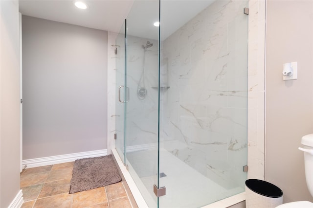 bathroom featuring a shower with door and toilet