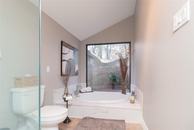 bathroom with tile patterned flooring, vaulted ceiling, tiled bath, and toilet