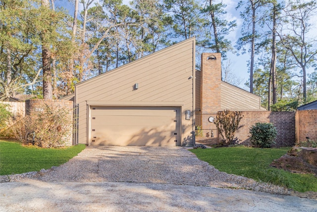 view of side of home featuring aphalt driveway, a fenced front yard, a lawn, a chimney, and a garage