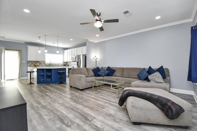 living room featuring crown molding, sink, ceiling fan, and light hardwood / wood-style flooring