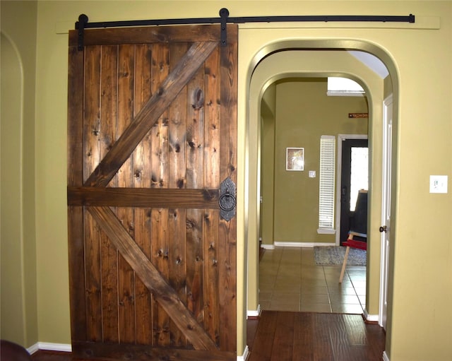 corridor with dark tile patterned floors and a barn door