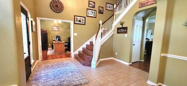 entryway with light tile patterned floors and a towering ceiling