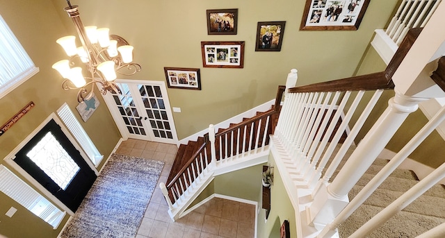 staircase featuring an inviting chandelier, plenty of natural light, tile patterned floors, and french doors