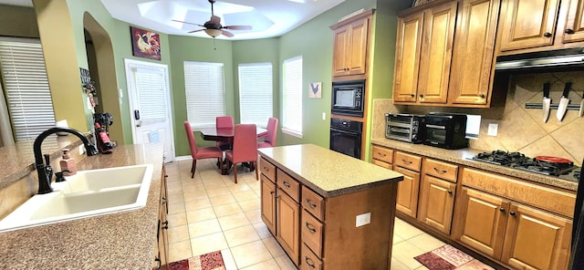 kitchen featuring sink, a kitchen island, black appliances, light tile patterned flooring, and decorative backsplash