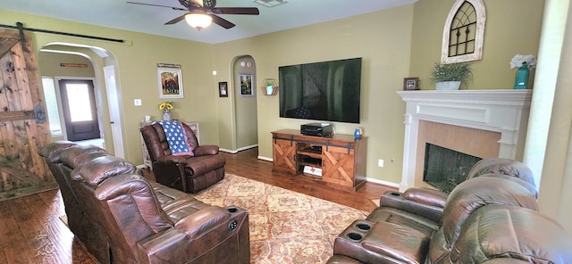 living room with hardwood / wood-style flooring, a barn door, and ceiling fan