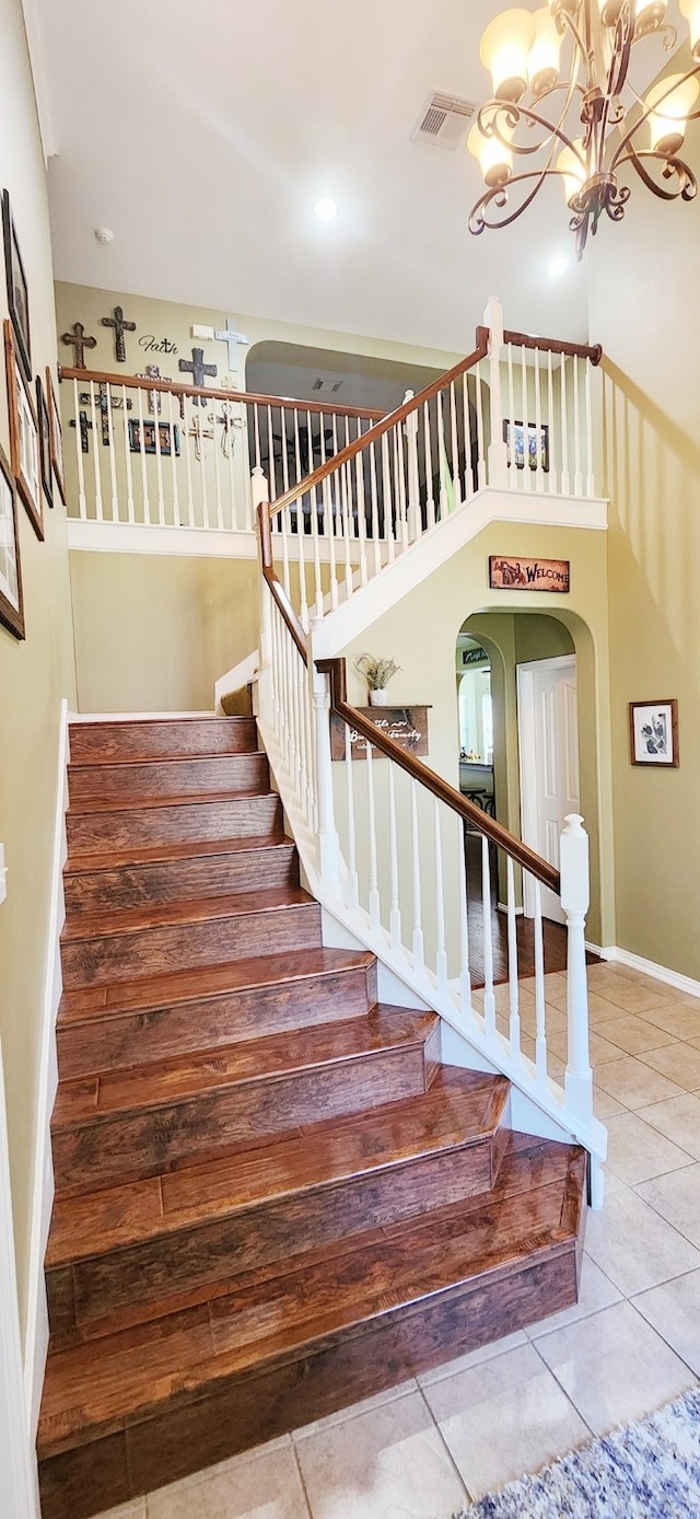 stairs featuring tile patterned floors and a chandelier